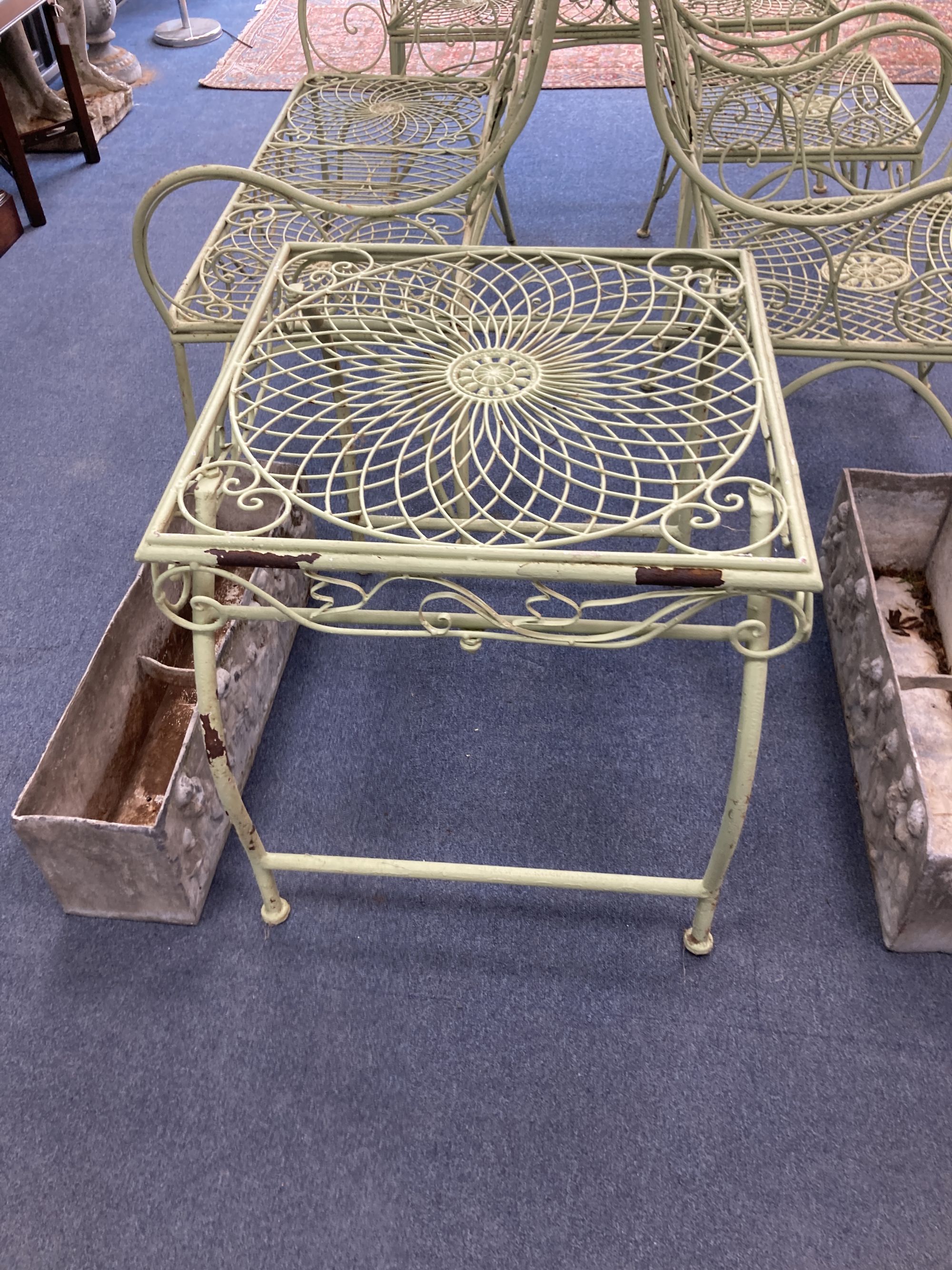 A French painted wrought iron garden suite comprising a pair of benches, length 122cm, depth 62cm, height 108cm, a pair of chairs and a table